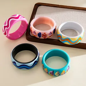 Detailed view of vibrant resin bangles featuring colorful wave patterns and tropical fish prints.