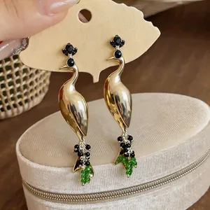 Detailed view of vintage peacock stud earrings with rhinestones and green beads.