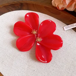 Detailed view of elegant large red resin flower earrings with textured gold stamens.