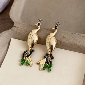 Detailed view of vintage gold peacock earrings featuring elegant green and black bead tassels.