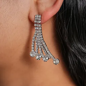 Close-up view of elegant silver rhinestone tassel earrings worn on a model's ear.