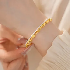 Primo piano di un braccialetto traforato in oro stile pizzo vintage sul polso