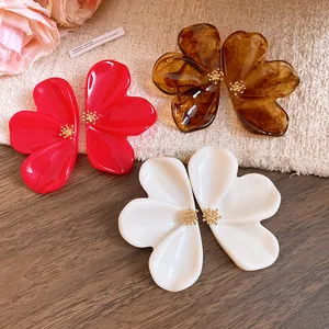 Close-up of elegant resin flower stud earrings in red, white and amber glossy finish