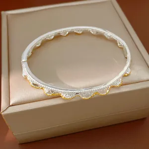 Dettaglio del design traforato in pizzo di un bracciale vintage in oro e argento.