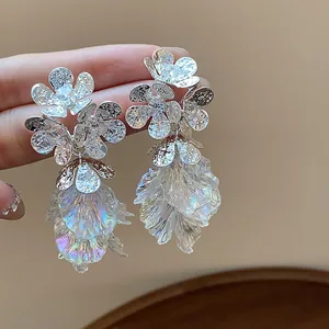 Close-up detail of shimmering iridescent petal tassel earrings with textured floral silver studs
