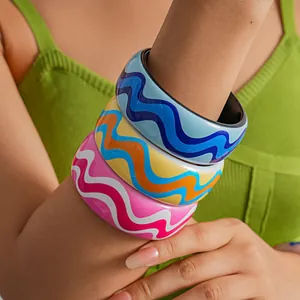 Close-up of stacked colorful resin bangles with vibrant wavy patterns on a model's arm