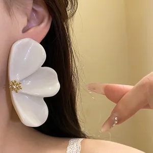 Close-up view of a large elegant white resin flower stud earring worn on a model ear