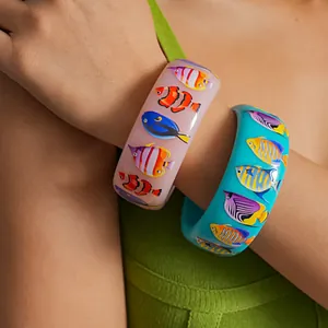 Detailed view of vibrant resin bangles featuring colorful tropical fish prints in dopamine style.