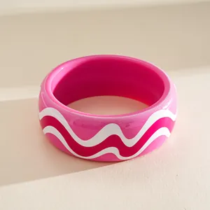 Close-up of pink resin bangle featuring white wave patterns and a smooth finish.
