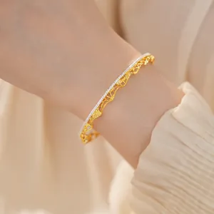 Primo piano che mostra la trama intricata di un bracciale traforato vintage in pizzo dorato.