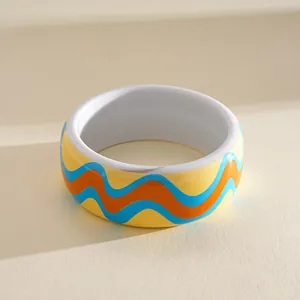 Close-up of colorful resin bangle with wave pattern in blue, orange, and yellow