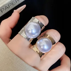 Macro view of elegant gold and silver wide-band rings featuring large iridescent purple pearls