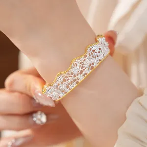 Dettaglio ravvicinato di bracciale rigido vintage traforato con bordo in pizzo al polso