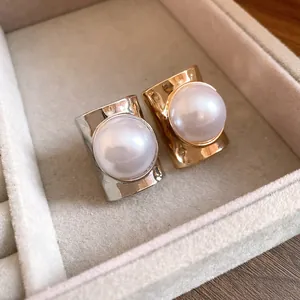 Detailed macro view of gold and silver wide band open rings with large pearls in a tray