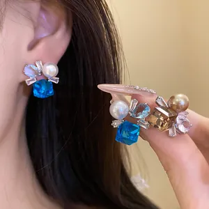 Elegant detail shot of retro silver earrings with blue crystal and pearls on Asian model.