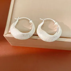 Primo piano di orecchini a cerchio minimalisti placcati oro 18K con elegante texture spazzolata