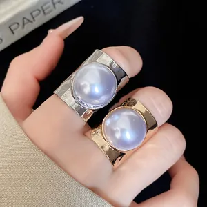 Close-up view of minimalist gold and silver open rings with large round purple pearls