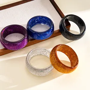 Macro detail of colorful resin bangles featuring embedded star and snowflake glitter.