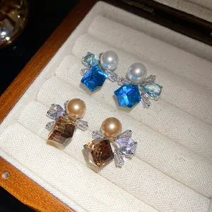 Macro detail of vintage blue and champagne crystal stud earrings with pearls in a box