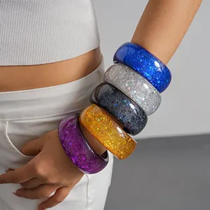 Detailed view of colorful chunky resin bangles with glitter and star motifs