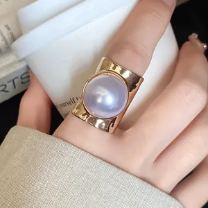Close-up of a luxury gold ring featuring a large purple pearl on an index finger