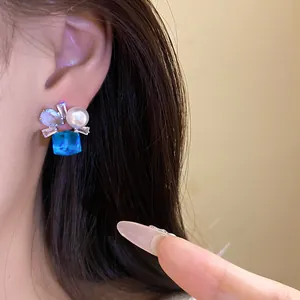 Macro view of blue square zircon and pearl earring detailing craftsmanship and shine