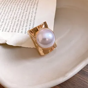 Detailed view of a minimalist gold-toned open ring with a large lustrous round pearl.