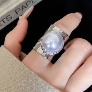 Detail view of a silver-toned hammered ring with a large lavender pearl, elegant style.
