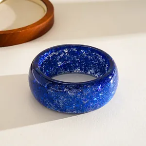 Macro detail view of blue resin bangle with shiny star and snowflake glitter patterns