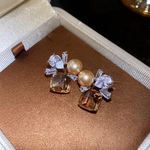 Detailed macro shot of vintage pearl earrings with amber square and teardrop stones.
