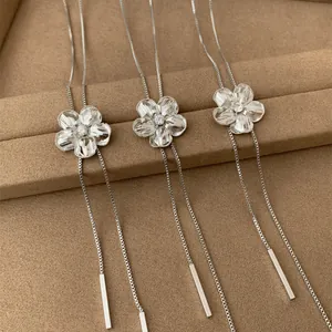 Gros plan détaillé de trois colliers à pampilles avec fleurs en strass argentées sur plateau.
