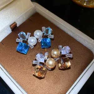 Elegant macro detail of vintage zircon pearl stud earrings in blue and amber hues