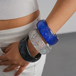 Close-up of three dopamine resin bangles with glitter stars and marbled textures