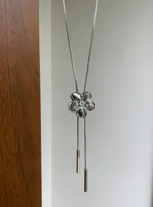 Gros plan d'un collier à pompon floral argenté avec une pierre centrale étincelante.