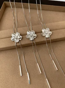 Gros plan détaillé de colliers à pompons fleurs en argent sur un plateau à bijoux brun