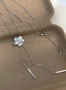 Détail montrant le pendentif fleur serti de diamants sur un collier à pompons argenté