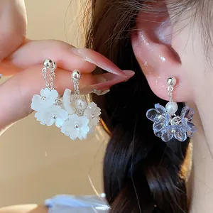 Close-up detail of elegant summer floral pearl earrings in soft white and blue shades