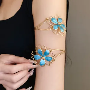 Detail shot of blue enamel flower arm cuff bracelets in gold-tone metal.