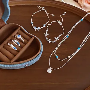 Elegant silver-tone jewelry set featuring blue zircon, pearls, and star charms on a wooden tray