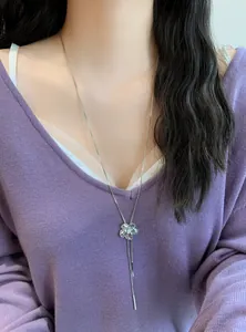 Vue détaillée d'un élégant collier à pompons argenté avec pendentif fleur en strass.