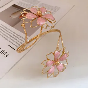 Close-up detail of the pink enamel flowers on this elegant golden metal spiral armlet.