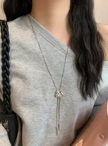 Vue détaillée d'un collier pampille fleur en argent porté sur un haut gris élégant