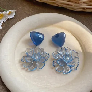 Elegant blue transparent resin flower earrings with pearl center in natural setting