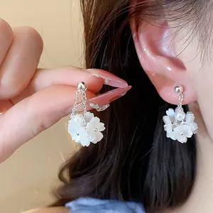 Close-up detail of elegant fresh flower pearl stud earrings with silver needles.