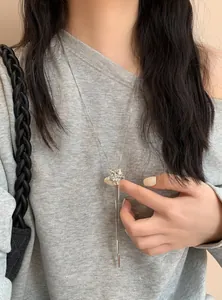 Gros plan d'un collier à pampilles en forme de fleur en strass argenté sur un sweat gris