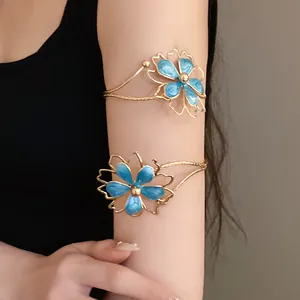 Elegant gold-toned upper arm cuff featuring blue enamel flower detail on model's arm.