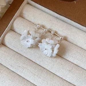 Close-up detail of elegant white floral stud earrings with silver pins in jewelry box