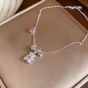 Detailed shot of a silver bear pendant necklace with sparkling pink zircon hearts.