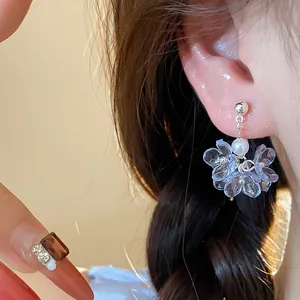 Detail showing elegant blue acrylic flower earrings with pearl accents on ear