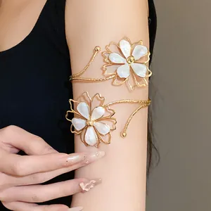Detail view of golden metal arm cuffs featuring pearlescent white dripping oil flowers.